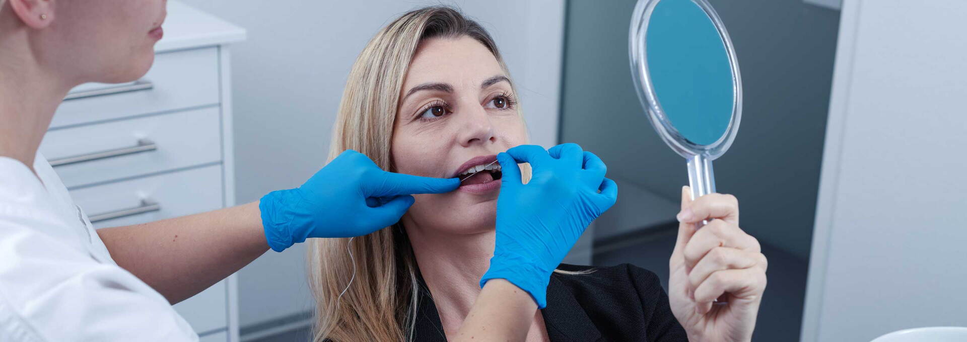 Dentalhygienikerin führt Zahnprophylaxe einer Patientin vor Dentalhygienikerin führt Zahnprophylaxe einer Patientin vor