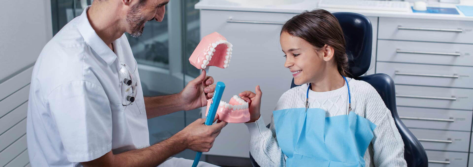 Kinderzahnarzt schult Kind im Zähneputzen Kinderzahnarzt schult Kind im Zähneputzen